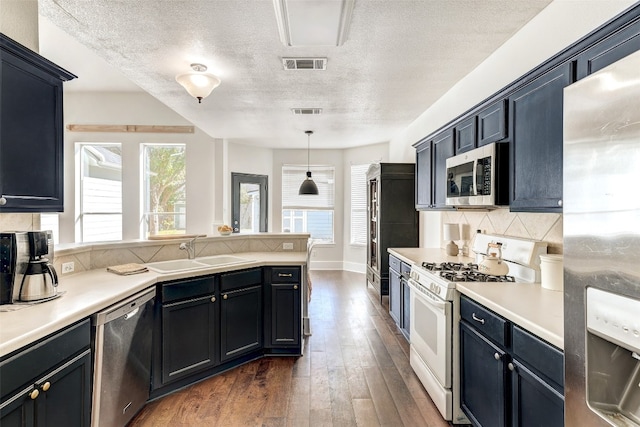 kitchen with sink, hanging light fixtures, dark hardwood / wood-style floors, a textured ceiling, and appliances with stainless steel finishes