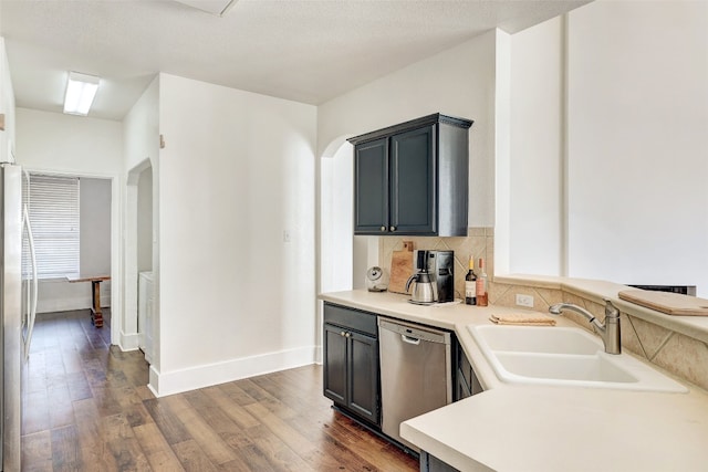 kitchen featuring backsplash, dark wood-type flooring, sink, a textured ceiling, and stainless steel appliances