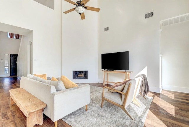 living room with hardwood / wood-style floors, ceiling fan, and a high ceiling