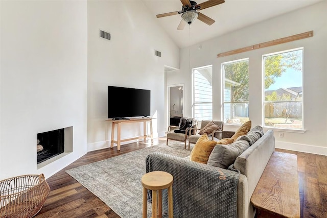 living room with high vaulted ceiling, ceiling fan, and dark wood-type flooring