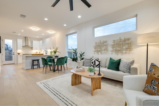 living room with sink, ceiling fan, and light wood-type flooring