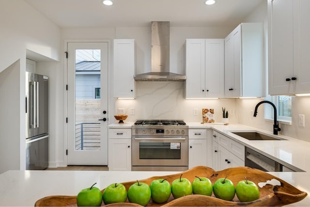 kitchen featuring sink, white cabinets, wall chimney range hood, tasteful backsplash, and high quality appliances