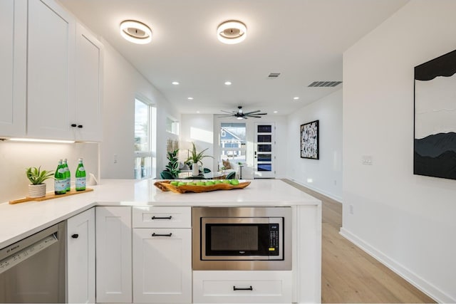 kitchen featuring stainless steel appliances, ceiling fan, light wood-type flooring, and white cabinetry