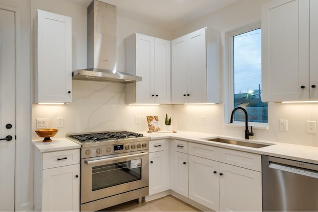 kitchen with wall chimney exhaust hood, white cabinetry, stainless steel appliances, and sink