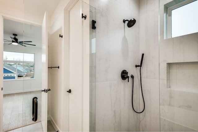 bathroom with a tile shower and ceiling fan