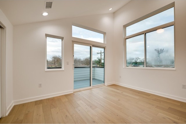 empty room featuring lofted ceiling and light hardwood / wood-style flooring