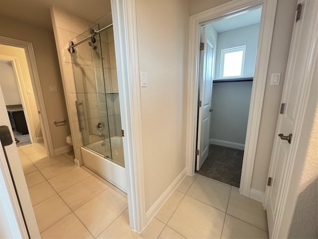 bathroom featuring tile patterned floors, toilet, and enclosed tub / shower combo