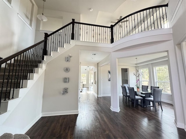 interior space featuring a chandelier, a towering ceiling, and dark wood-type flooring