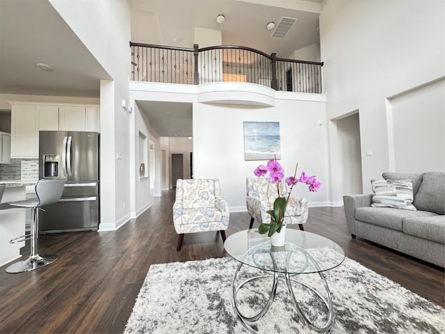 living room with a towering ceiling and dark hardwood / wood-style floors