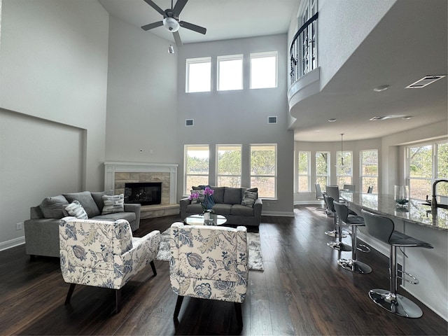 living room featuring a wealth of natural light, a fireplace, ceiling fan, and a high ceiling