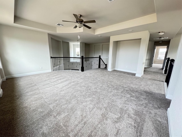 spare room with ceiling fan, light carpet, and a tray ceiling