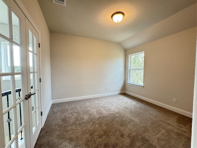 carpeted empty room with french doors, a textured ceiling, and lofted ceiling