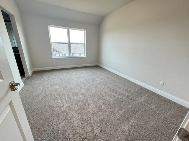 unfurnished room with carpet and vaulted ceiling