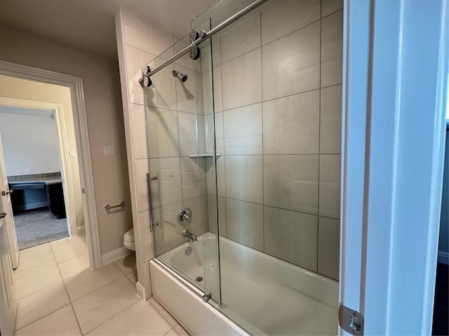 bathroom featuring tile patterned flooring, toilet, and bath / shower combo with glass door