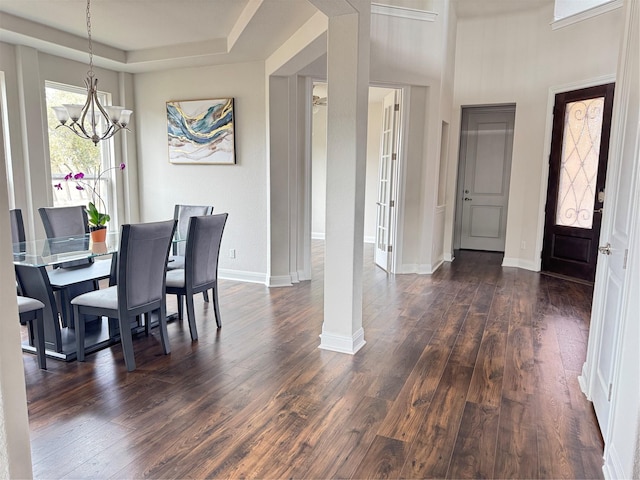 dining area featuring a chandelier, a raised ceiling, and dark wood-type flooring