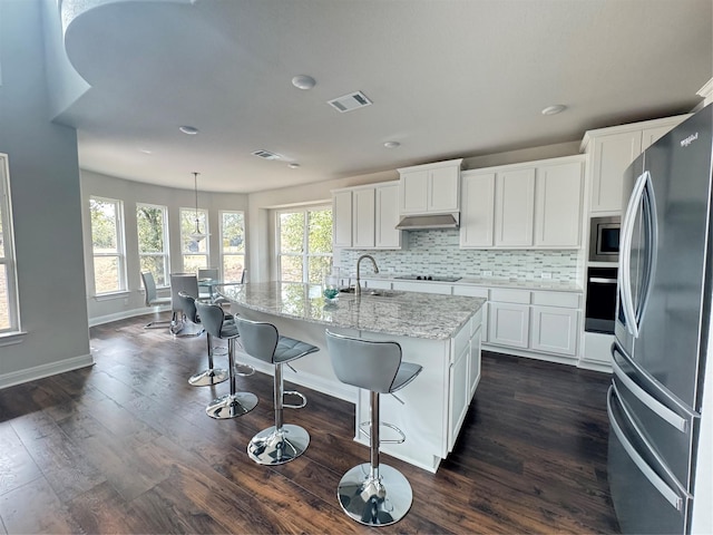 kitchen with a kitchen island with sink, white cabinetry, stainless steel appliances, and hanging light fixtures