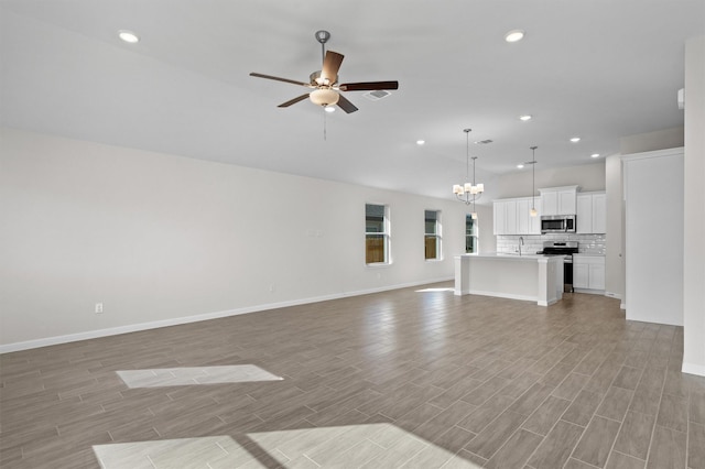 unfurnished living room featuring light wood-style floors, recessed lighting, vaulted ceiling, and ceiling fan with notable chandelier