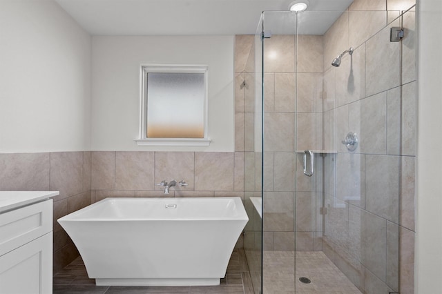 bathroom with plus walk in shower, vanity, and tile walls