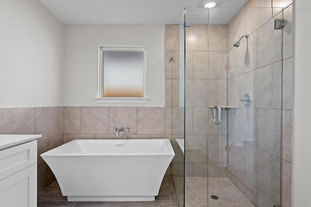 full bath featuring a shower stall, tile walls, a freestanding bath, and vanity