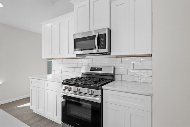 kitchen featuring hardwood / wood-style flooring, white cabinetry, backsplash, and appliances with stainless steel finishes