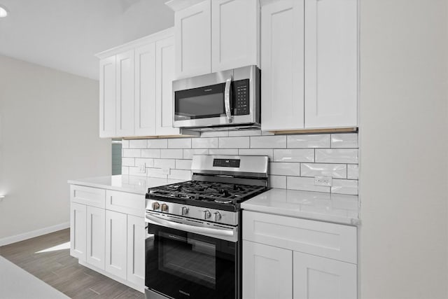 kitchen featuring wood finished floors, stainless steel appliances, decorative backsplash, and light countertops