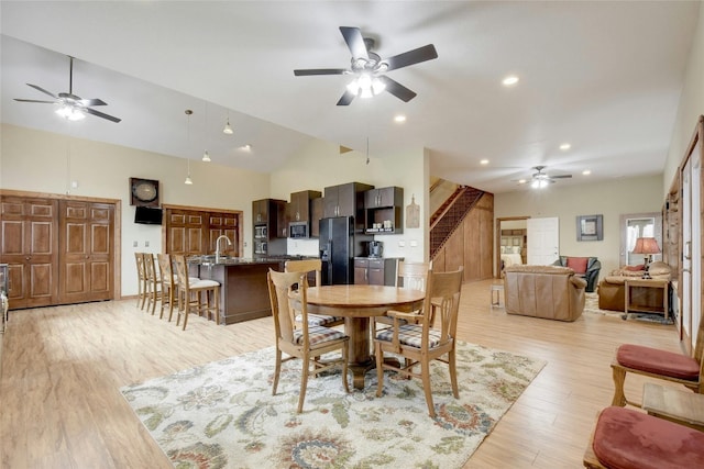 dining space with ceiling fan, high vaulted ceiling, and light wood-type flooring