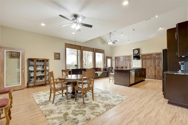 dining room with ceiling fan, high vaulted ceiling, sink, and light wood-type flooring