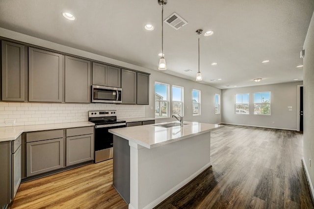 kitchen with appliances with stainless steel finishes, decorative light fixtures, plenty of natural light, and light wood-type flooring