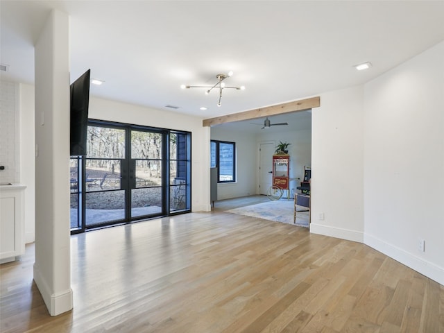 unfurnished room featuring french doors, ceiling fan with notable chandelier, and light hardwood / wood-style floors