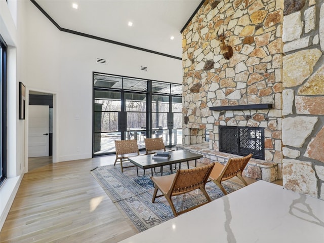 dining space with a fireplace, light hardwood / wood-style floors, a towering ceiling, and french doors