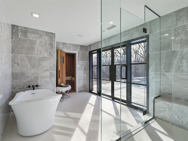 bathroom featuring tile patterned floors, a bathing tub, and tile walls