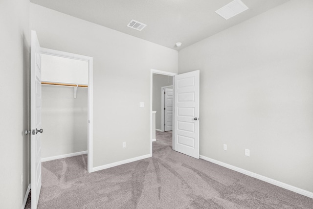 unfurnished bedroom with a closet, light carpet, and a spacious closet