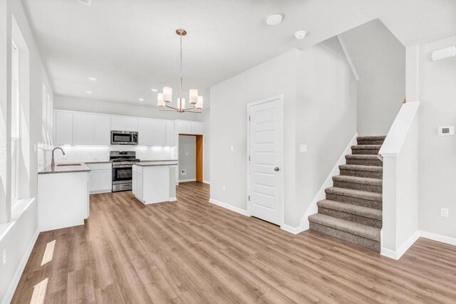 kitchen with light hardwood / wood-style floors, appliances with stainless steel finishes, white cabinetry, and a center island