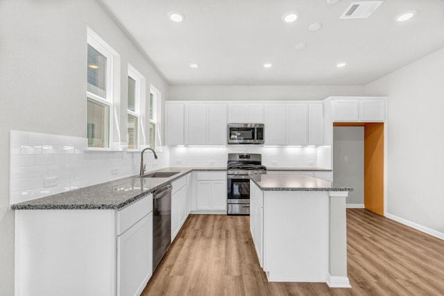 kitchen featuring sink, appliances with stainless steel finishes, light wood-type flooring, and a center island