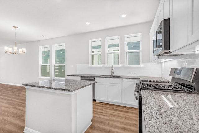 kitchen featuring light hardwood / wood-style floors, backsplash, stainless steel appliances, and a healthy amount of sunlight