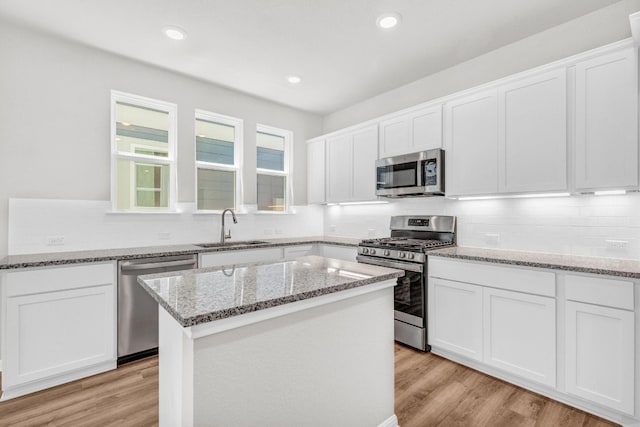 kitchen featuring appliances with stainless steel finishes, light hardwood / wood-style flooring, white cabinets, and tasteful backsplash