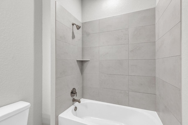 bathroom featuring tiled shower / bath and toilet