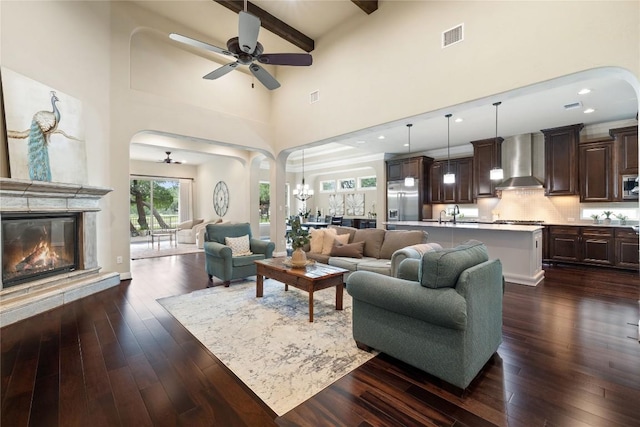 living room featuring ceiling fan with notable chandelier, beam ceiling, dark hardwood / wood-style floors, and high vaulted ceiling