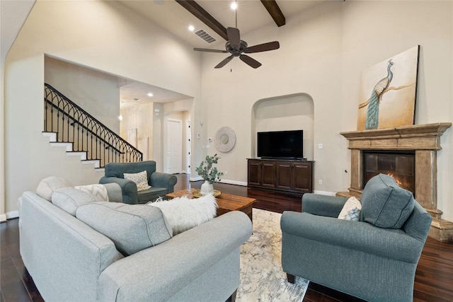 living room featuring beamed ceiling, dark hardwood / wood-style floors, ceiling fan, and a high ceiling