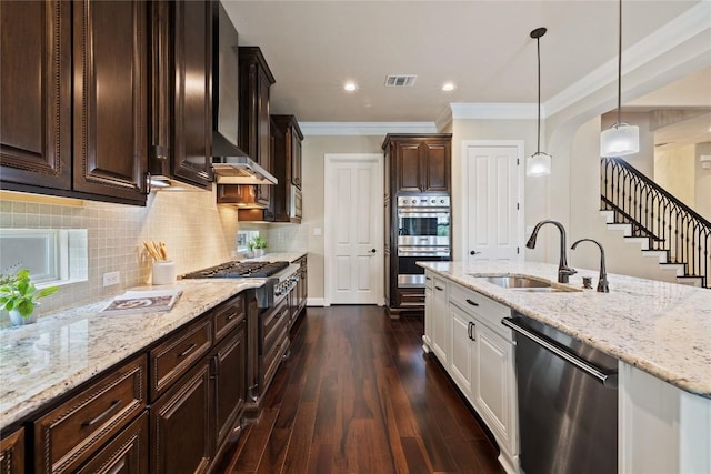 kitchen featuring dark wood-type flooring, hanging light fixtures, sink, appliances with stainless steel finishes, and white cabinetry