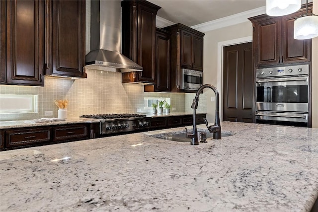 kitchen with light stone countertops, stainless steel appliances, wall chimney range hood, a sink, and crown molding