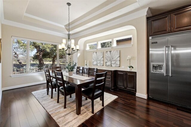dining area featuring dark wood-type flooring, baseboards, a notable chandelier, crown molding, and a tray ceiling