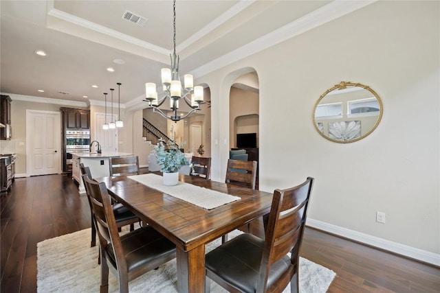 dining area with visible vents, a chandelier, arched walkways, ornamental molding, and dark wood-type flooring