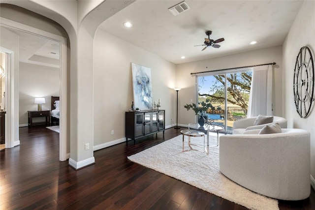 living room with ceiling fan and dark wood-type flooring