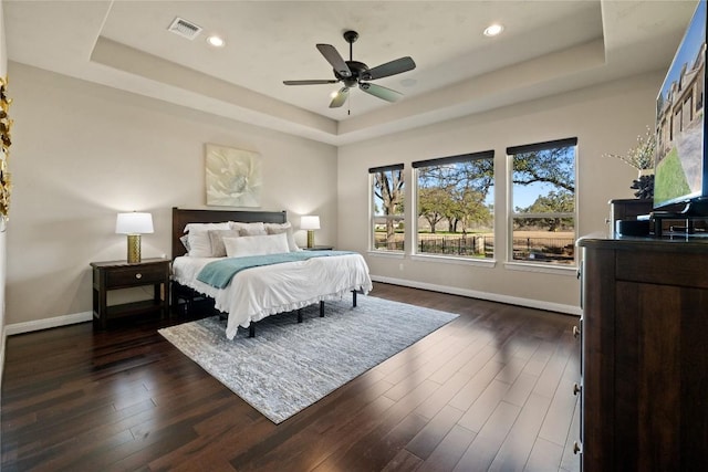 bedroom with visible vents, a tray ceiling, baseboards, recessed lighting, and dark wood-type flooring