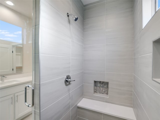 bathroom featuring plenty of natural light, vanity with extensive cabinet space, and tiled shower