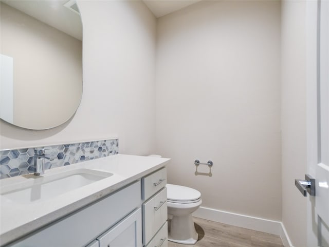 bathroom with toilet, wood-type flooring, tasteful backsplash, and vanity