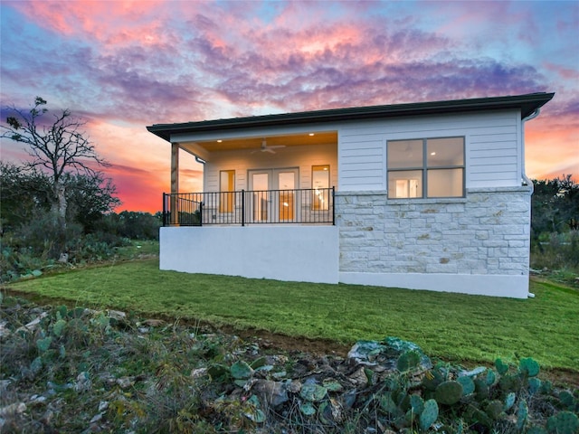 back house at dusk with a yard and ceiling fan