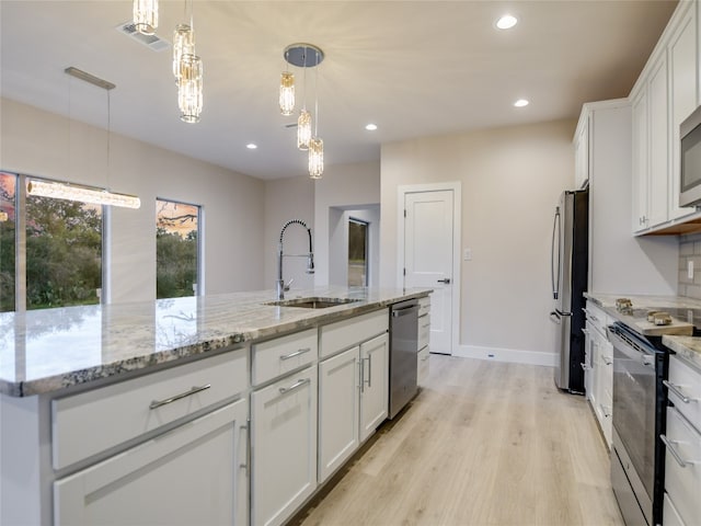 kitchen featuring light hardwood / wood-style floors, stainless steel appliances, a center island with sink, white cabinetry, and sink