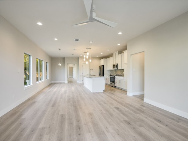 unfurnished living room with ceiling fan, sink, and light hardwood / wood-style flooring